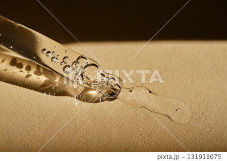 A pipette with cosmetic serum on a beige background. A pipette with cosmetic serum on a beige background. 131918075