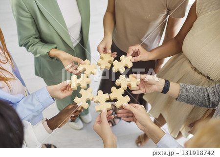 Diverse team hands connecting wooden puzzle pieces in a circle, symbolizing unity Diverse team hands connecting wooden puzzle pieces in a circle, symbolizing unity 131918742