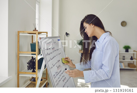 Young woman standing in office next to white board with weekly plan and tasks 131919161