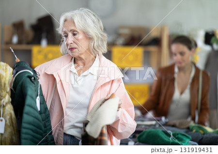 During November sales, senior woman choose and buy down coat During November sales, senior woman choose and buy down coat 131919431