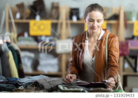 Young woman choosing woolen pants in store Young woman choosing woolen pants in store 131919433