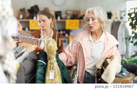 Two female clients customer examine and choose something autumn warm outwear in store Two female clients customer examine and choose something autumn warm outwear in store 131919467