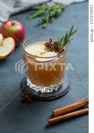 Hot apple cider with cinnamon, anise, and rosemary in glass on a dark blue background with fruits Hot apple cider with cinnamon, anise, and rosemary in glass on a dark blue background with fruits 131919501