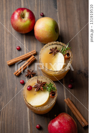 Two glasses of hot apple cider with cinnamon, anise, brown sugar and rosemary on a wooden background Two glasses of hot apple cider with cinnamon, anise, brown sugar and rosemary on a wooden background 131919510