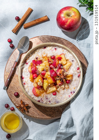 Overnight oatmeal with apples, cranberries, and cinnamon in a bowl on a wooden board Overnight oatmeal with apples, cranberries, and cinnamon in a bowl on a wooden board 131919514