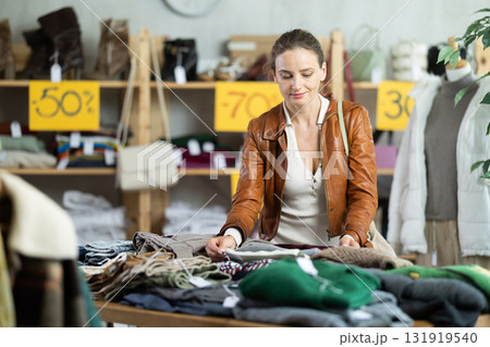 European woman customer examine and choose sweater in store European woman customer examine and choose sweater in store 131919540