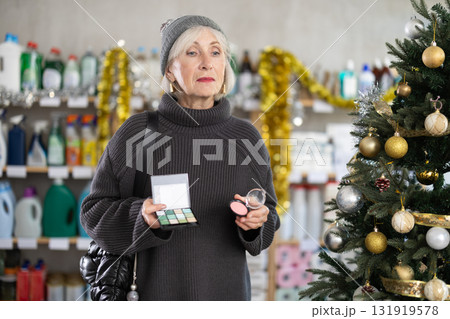 Elderly woman chooses cosmetics in decorated household chemicals store Elderly woman chooses cosmetics in decorated household chemicals store 131919578