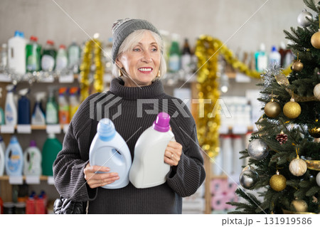 Elderly woman buyer chooses detergent in decorated household chemicals store 131919586