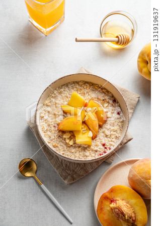 Oatmeal with peaches and nuts in a bowl on a light background with honey Oatmeal with peaches and nuts in a bowl on a light background with honey 131919637