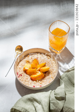 Oatmeal with peaches and nuts in a bowl on a light background with honey Oatmeal with peaches and nuts in a bowl on a light background with honey 131919642