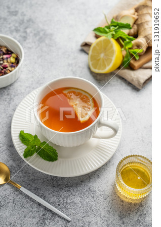 Tea with lemon, ginger, honey, and mint in a cup on a gray background with citrus fruits and herbs. 131919652