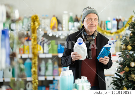 On New Year Eve, senior man studies label and choose kitchen cleaner spray and liquid detergent On New Year Eve, senior man studies label and choose kitchen cleaner spray and liquid detergent 131919852