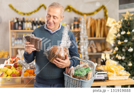 Portrait of mature man buying chocolate and chocolate candies for gift and celebrating Christmas 131919888