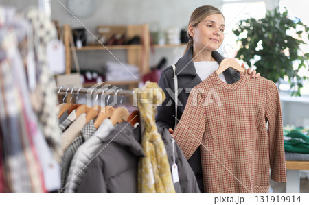 Adult woman chooses warm dress in clothing store Adult woman chooses warm dress in clothing store 131919914