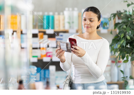 Asian woman scans on mobile makeup packaging 131919930