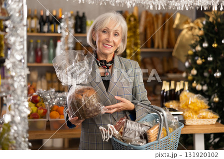 While shopping on eve of New Year holidays, elderly lady is interested in packing panettone. 131920102