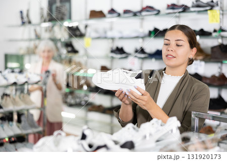In multi-brand leather goods store,girl chooses modern comfortable running sneakers for fitness In multi-brand leather goods store,girl chooses modern comfortable running sneakers for fitness 131920173