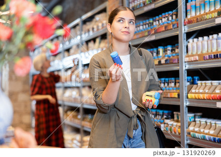 Female customer chooses multi-colored pigments for her future earthenware or ceramic tableware in specialty store Female customer chooses multi-colored pigments for her future earthenware or ceramic tableware in specialty store 131920269