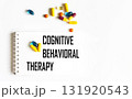 The text "COGNITIVE BEHAVIORAL THERAPY" is written in a notebook next to pills. Medical concept 131920543