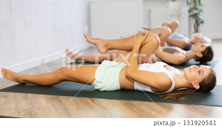 Women three generations doing different yoga exercises lying on back Women three generations doing different yoga exercises lying on back 131920581