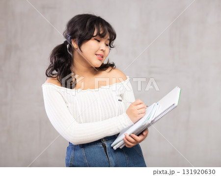 Smiling young girl making notes in studio 131920630