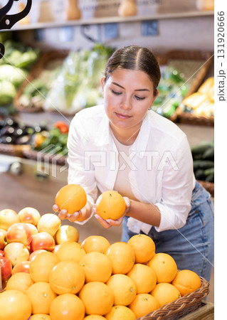 Young girl selecting ripe oranges while shopping in supermarket Young girl selecting ripe oranges while shopping in supermarket 131920666