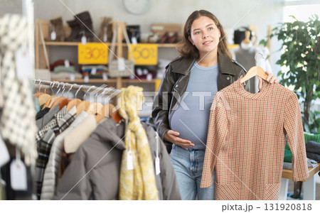 Pregnant woman choosing winter dress in clothing store 131920818