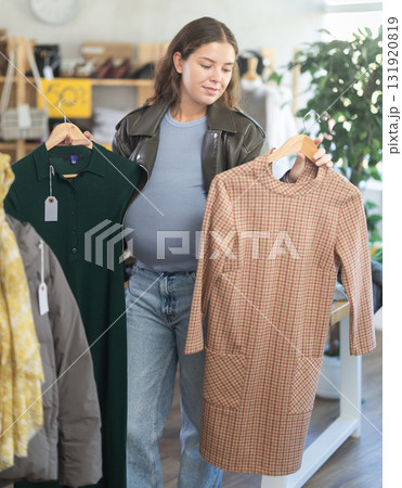 Pregnant woman choosing winter dress in clothing store 131920819