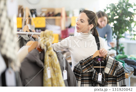 Woman chooses checkered jacket searches for fashionable clothes in clothing boutique 131920842