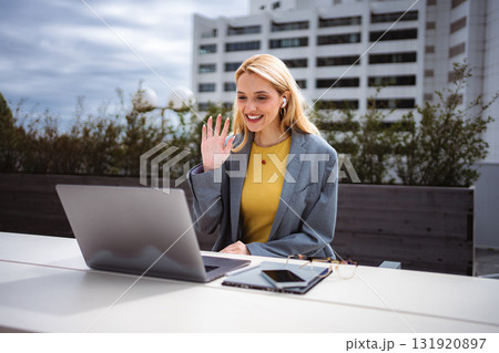 Businesswoman having video call on laptop outdoors waving Businesswoman having video call on laptop outdoors waving 131920897