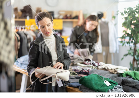 Selective middle-aged woman choosing handbag in clothing store 131920900