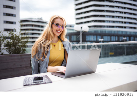 Businesswoman working on laptop on urban building rooftop Businesswoman working on laptop on urban building rooftop 131920915