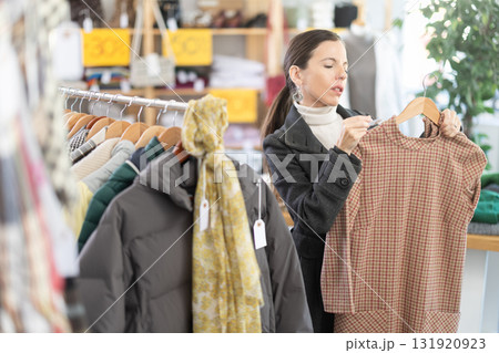 Adult woman chooses warm dress in clothing store 131920923