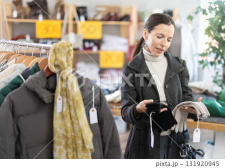 Woman carefully selects warm winter gloves in clothing store Woman carefully selects warm winter gloves in clothing store 131920945