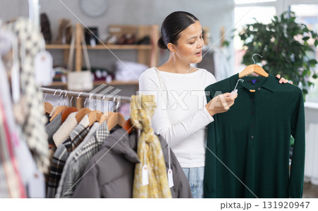 Asian woman browsing goods items and choose elect dress for autumn Asian woman browsing goods items and choose elect dress for autumn 131920947