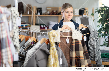 Adult woman chooses plaid jacket in clothing store Adult woman chooses plaid jacket in clothing store 131921047