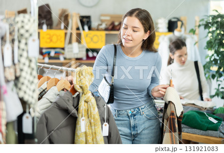 Young woman chooses different winter clothes in clothing store Young woman chooses different winter clothes in clothing store 131921083