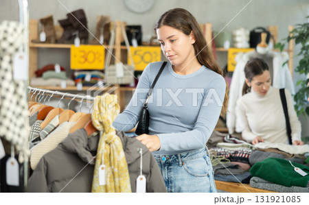 Young woman chooses different winter clothes in clothing store Young woman chooses different winter clothes in clothing store 131921085