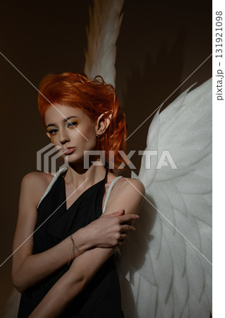 Beautiful woman with angel wings in a studio environment, showcasing elegance 131921098