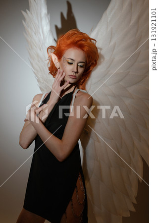 Beauty woman poses topless with angel wings in a creative studio setting 131921101