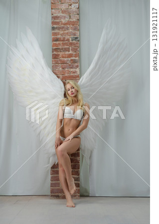 Beautiful woman with angel wings poses in studio setting 131921117