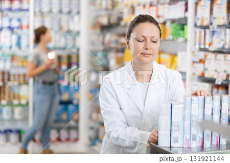 Pharmacy employee puts new healing body cosmetics on shelves 131921144