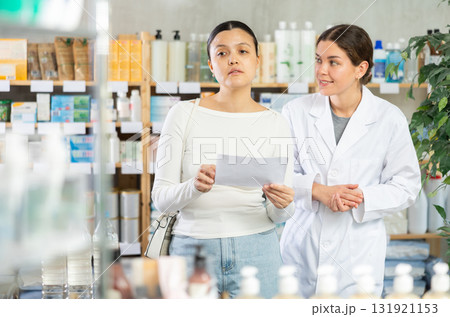 Young woman with prescription looking for medicines in pharmacy 131921153