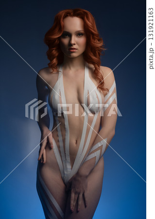 Stunning woman showcases body art with tape and fur in studio setting Stunning woman showcases body art with tape and fur in studio setting 131921163
