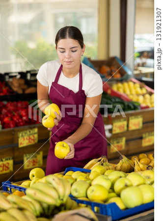 Smiling girl seller is showing assortment of apples in vegetable shop Smiling girl seller is showing assortment of apples in vegetable shop 131921307