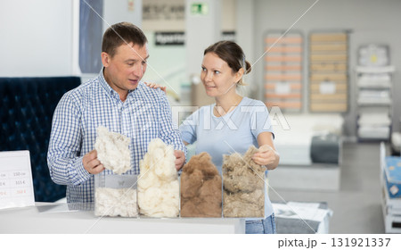 Married couple chooses and discusses mattress filling in furniture store 131921337