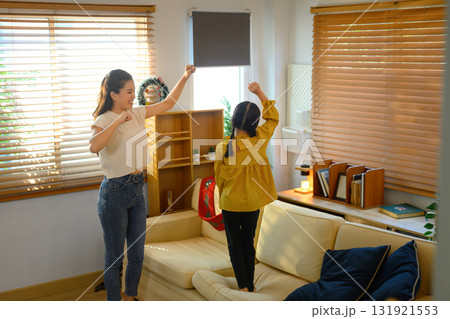 Asian mother and daughter dancing happily together in the living room 131921553