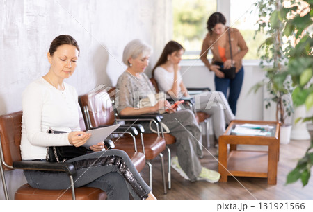 Adult woman with documents waiting for her turn on chair Adult woman with documents waiting for her turn on chair 131921566
