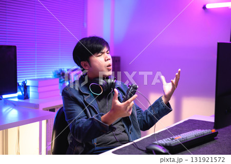 A young man enjoying playing computer games in a neon-lit room. The gaming atmosphere features vibrant colors A young man enjoying playing computer games in a neon-lit room. The gaming atmosphere features vibrant colors 131921572