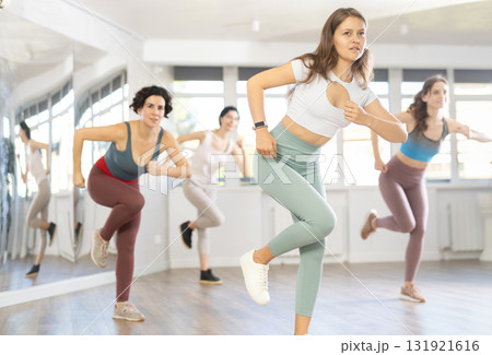 Cheerful young female instructor leading Zumba class for women 131921616